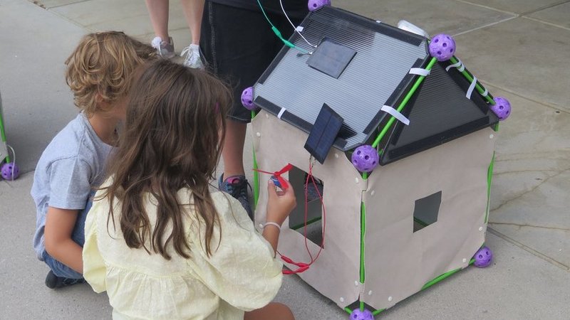 Kinder vor einem Solarbetriebenen Modellhaus
